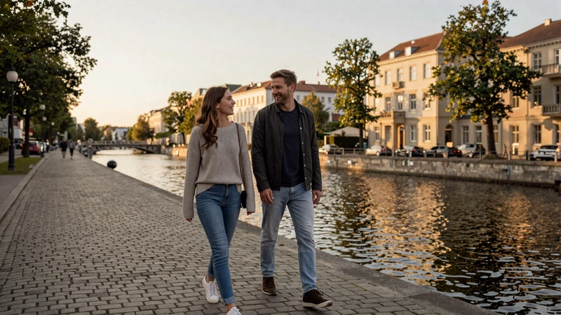 American man and German woman walking together along a Berlin canal at sunset - authentic German dating experience
